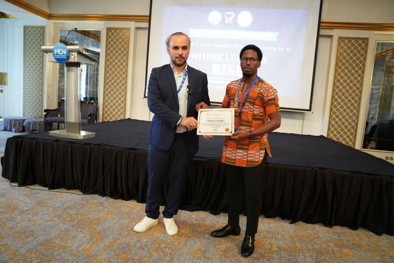 A summit volunteer receiving a certificate of achievement on stage in Dubai.