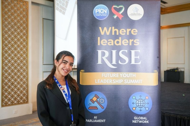 A delegate standing in front of the Where Leaders Rise summit banner.