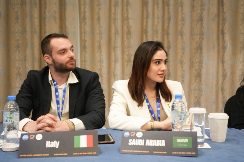 Two panellists at the delegate table during a summit session.