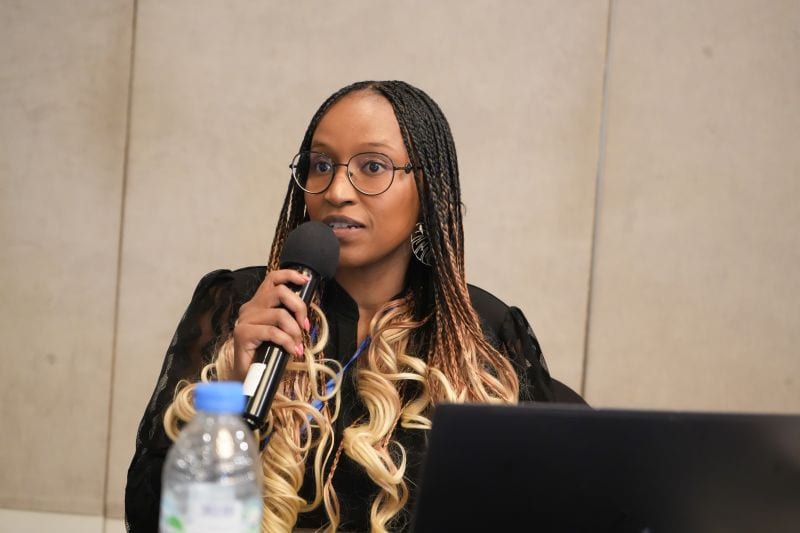 A speaker addressing the room with a microphone at the summit.