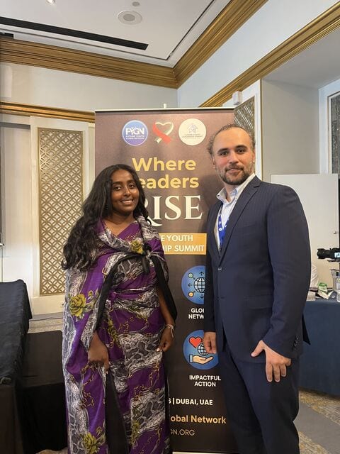 Two delegates in front of the Where Leaders Rise banner at the summit.
